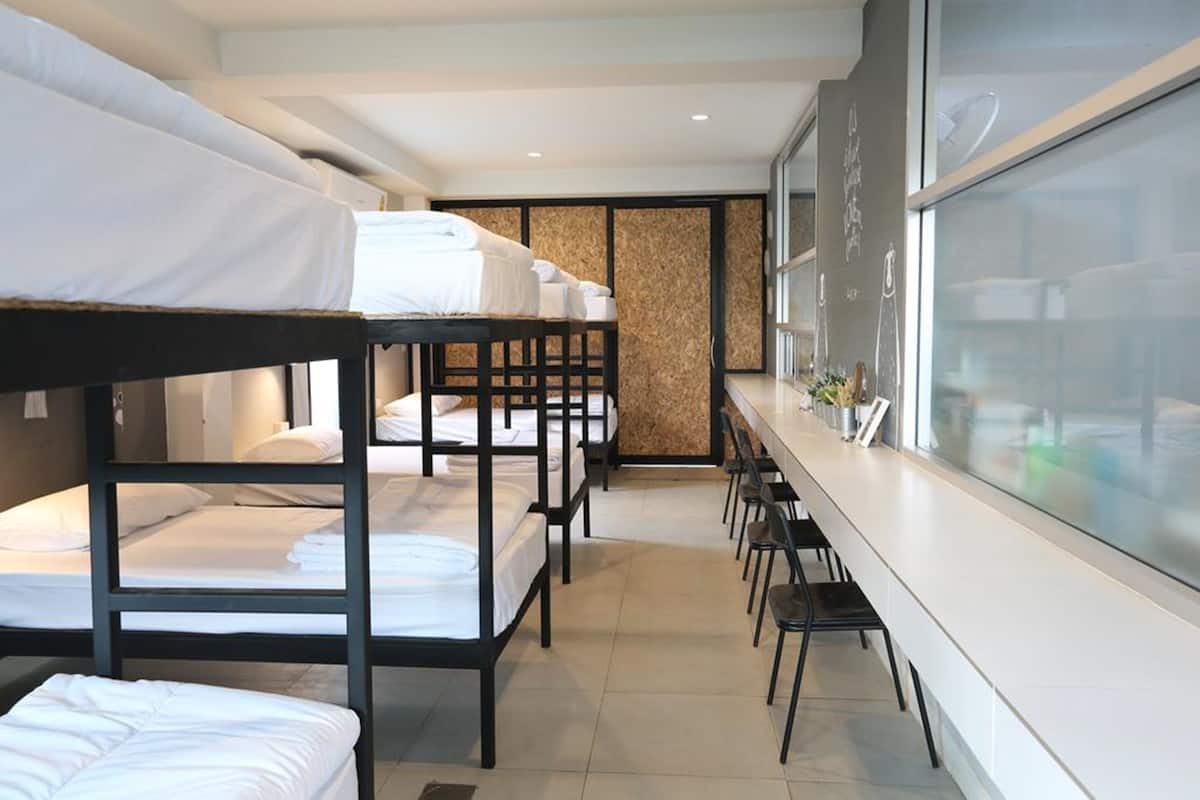 Ein Hotelzimmer mit Stockbetten, einer langen Theke mit Stühlen und einem großen Fenster.