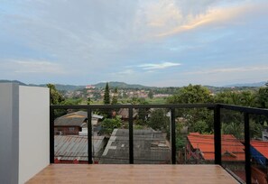 Ein Balkon mit Blick auf ein Wohngebiet und sanfte Hügel in der Ferne.