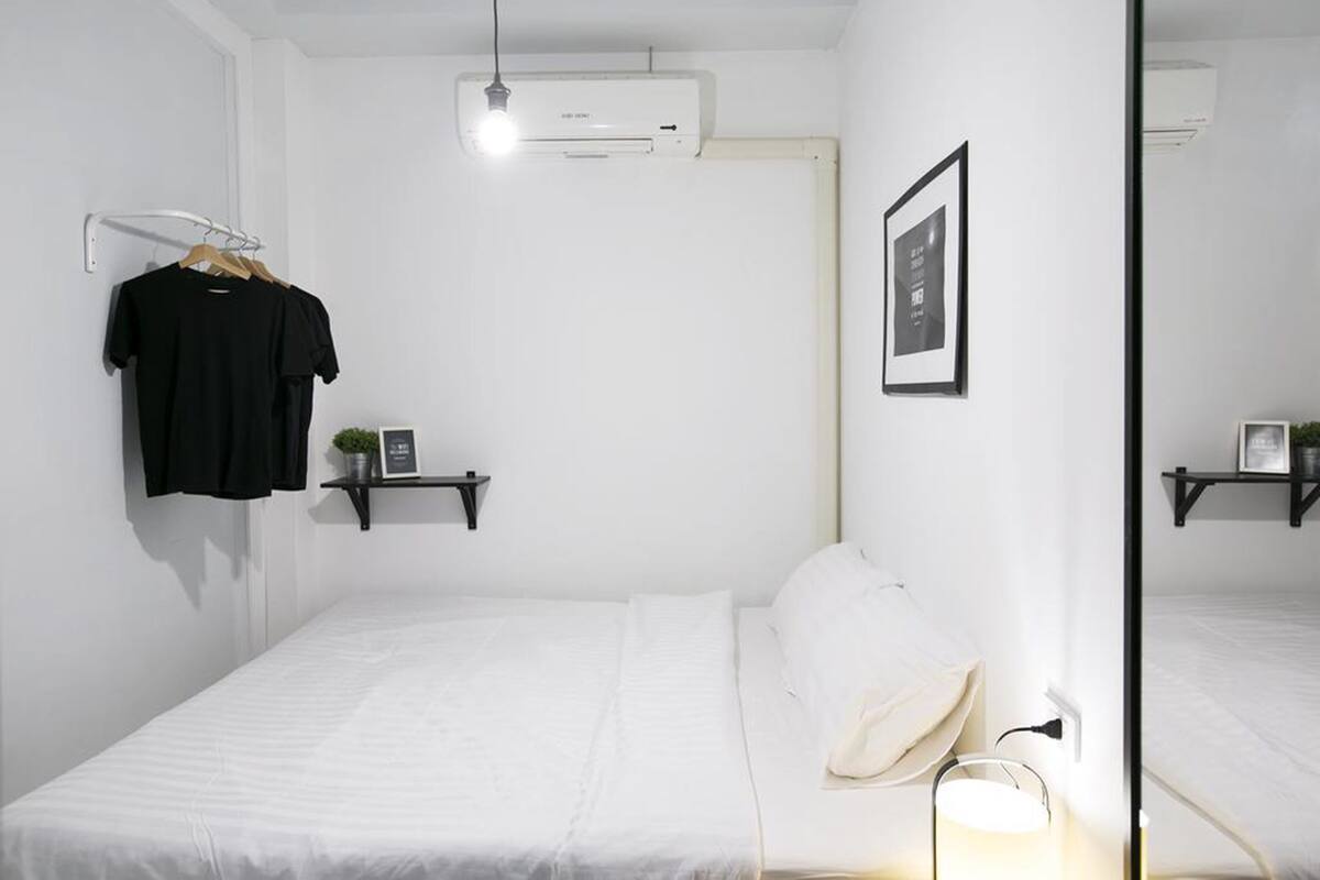 Ein schlichter Schlafzimmer mit Bett, einer Pendelleuchte, einer Wand-Klimaanlage und einem gerahmten Bild.