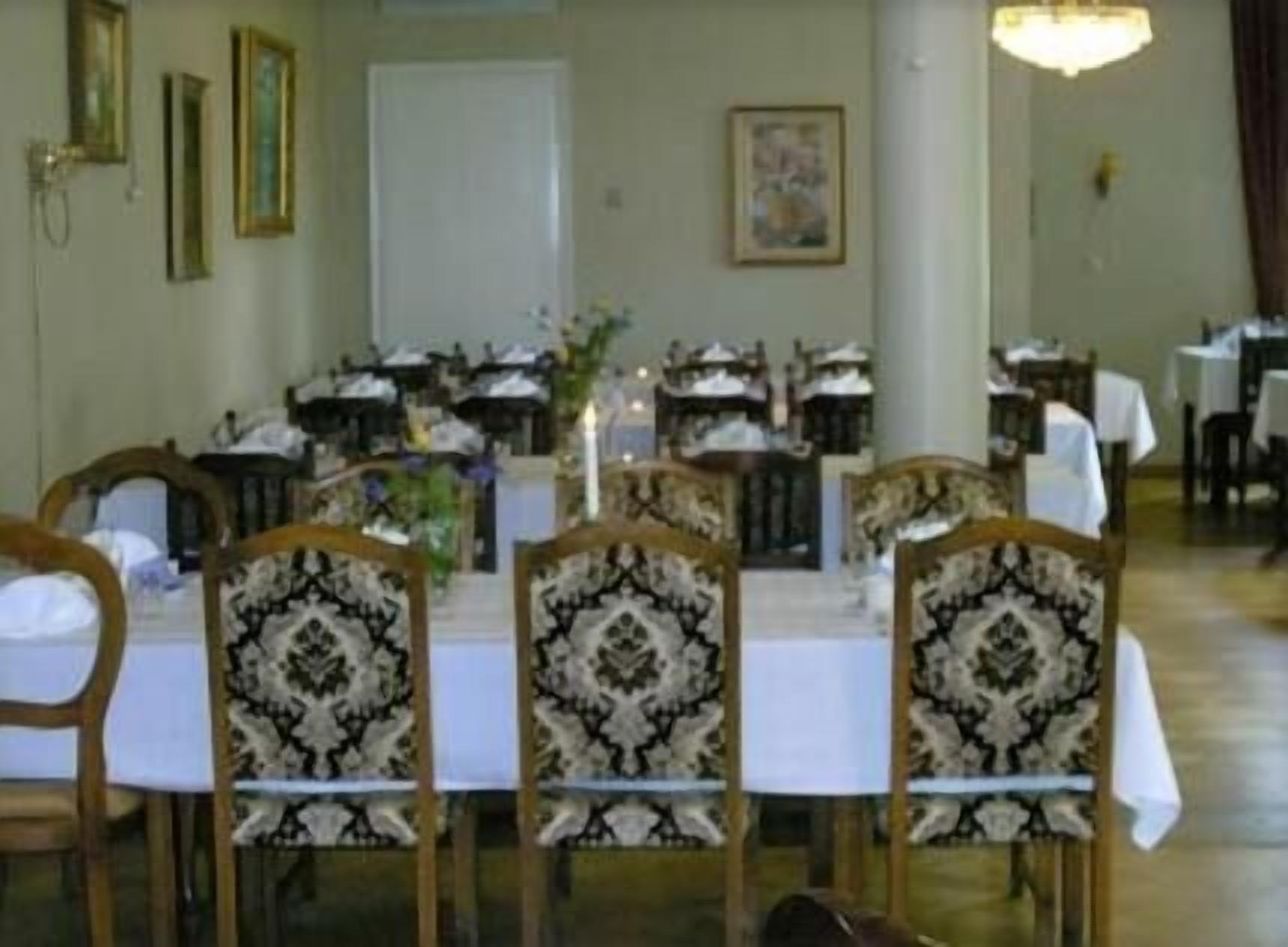 Un comedor con mesas redondas, sillas y un candelabro.