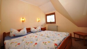 A bedroom with a bed, two wall-mounted lamps, a window, and a radiator. - Holiday home Bodden 47003 - Thatched cottage 47001 (Middelhagen)