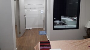 A narrow hallway leading to a bathroom with a window, a towel rack, and a bed with a patterned bedspread. - New Loft Modern Home (Hang Dong)