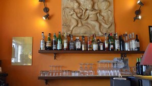 Un espace bar agrémenté d’une grande sculpture, d’étagères remplies de bouteilles d’alcool et de verres.
