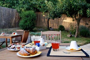 An outdoor dining area with a table set for breakfast, including pastries, condiments, and beverages. - Locanda all'Andreas (Manciano)