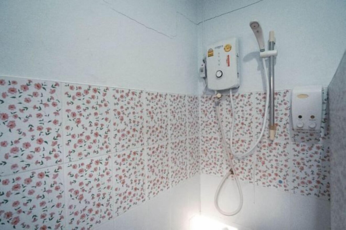 Ein Badezimmer mit Fliesen mit Blumenmuster, eine Dusche mit Duschbrausehandstück und einer Bedienkonsole.