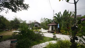 A garden area with a paved walkway, a bench, and various plants. - Long Lake Resort (Si Racha)