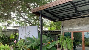 A Long Lake Resort entrance with a covered patio area, large potted plants, and a stone pathway leading to the entrance. - Long Lake Resort (Si Racha)