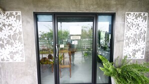 A building entrance with a glass door, a sign indicating WiFi availability, and a small outdoor seating area with chairs. - Long Lake Resort (Si Racha)