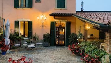 Ein gemütlicher Innenhof mit Backsteinfassade, grünen Fensterläden und Sitzgelegenheiten im Freien.