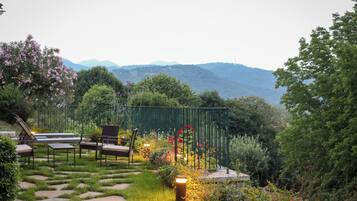 Ein Garten mit Sitzgelegenheit, einem Weg und Blick auf die Berge.