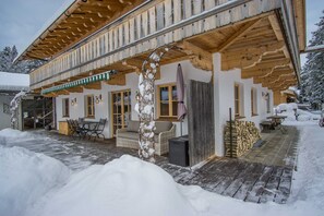 Un chalet en bois doté d’un patio couvert, d’un espace salon extérieur et où la neige s’accumule.