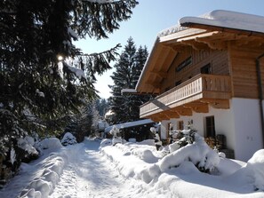Un bâtiment en bois recouvert de neige, doté d’un balcon, et entouré d’arbres chargés de neige.