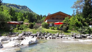 A wooden building with a sign 'Ferienwohnung' and outdoor seating with red umbrellas.
