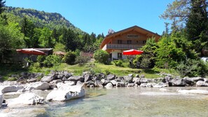 Un bâtiment en bois avec une enseigne indiquant « Ferienwohnung » et un espace extérieur aménagé avec des parasols rouges.