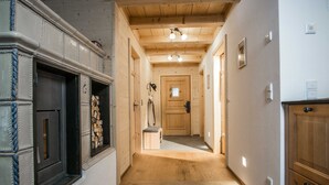 A hallway with wooden flooring, a wooden door at the end, and a small bench.