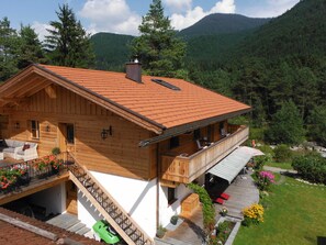 A wooden chalet with a balcony, a staircase, and a garden area. - Apartment 2 - Ground floor - Apartment Tegernsee, Family Schneider, Kreuth (Kreuth)
