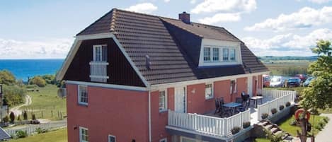 A two-story house with a balcony, a garage, and a view of the sea.