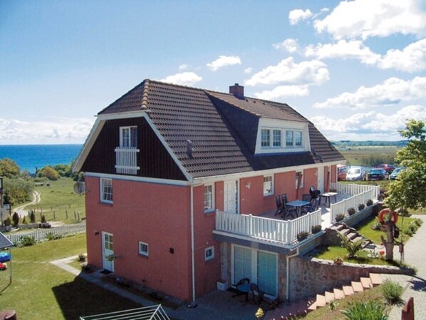 Una casa de dos pisos con balcón, garaje y vista al mar.