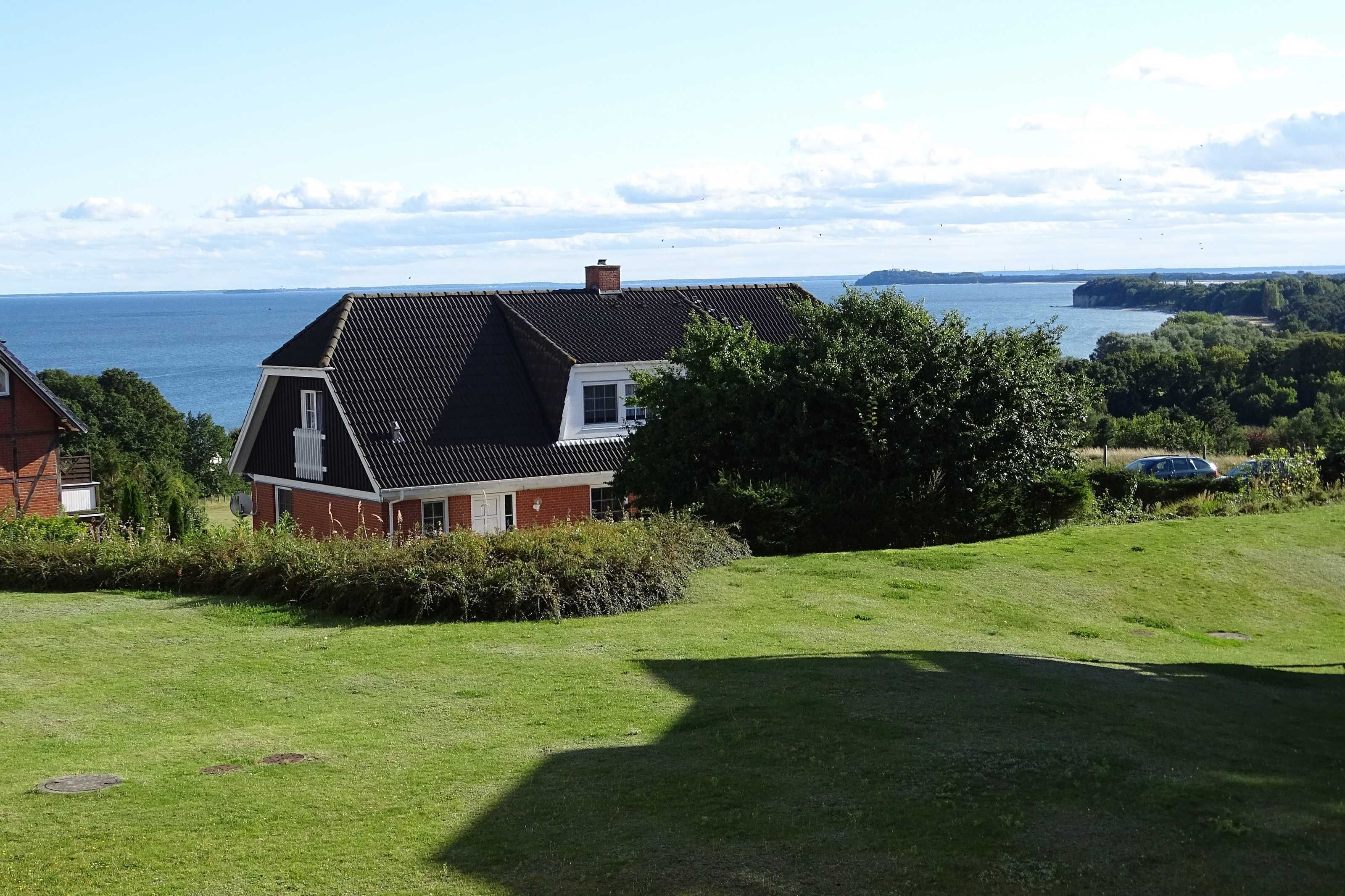 Una casa con techo inclinado, chimenea y vista al mar.