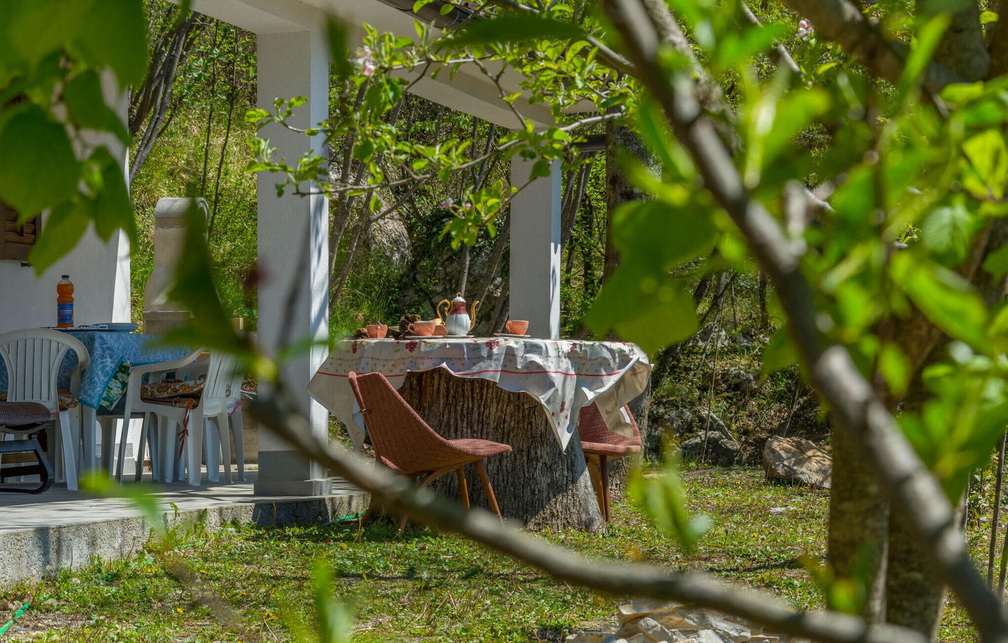 Un área de comedor al aire libre con una mesa preparada para dos personas, rodeada de follaje.