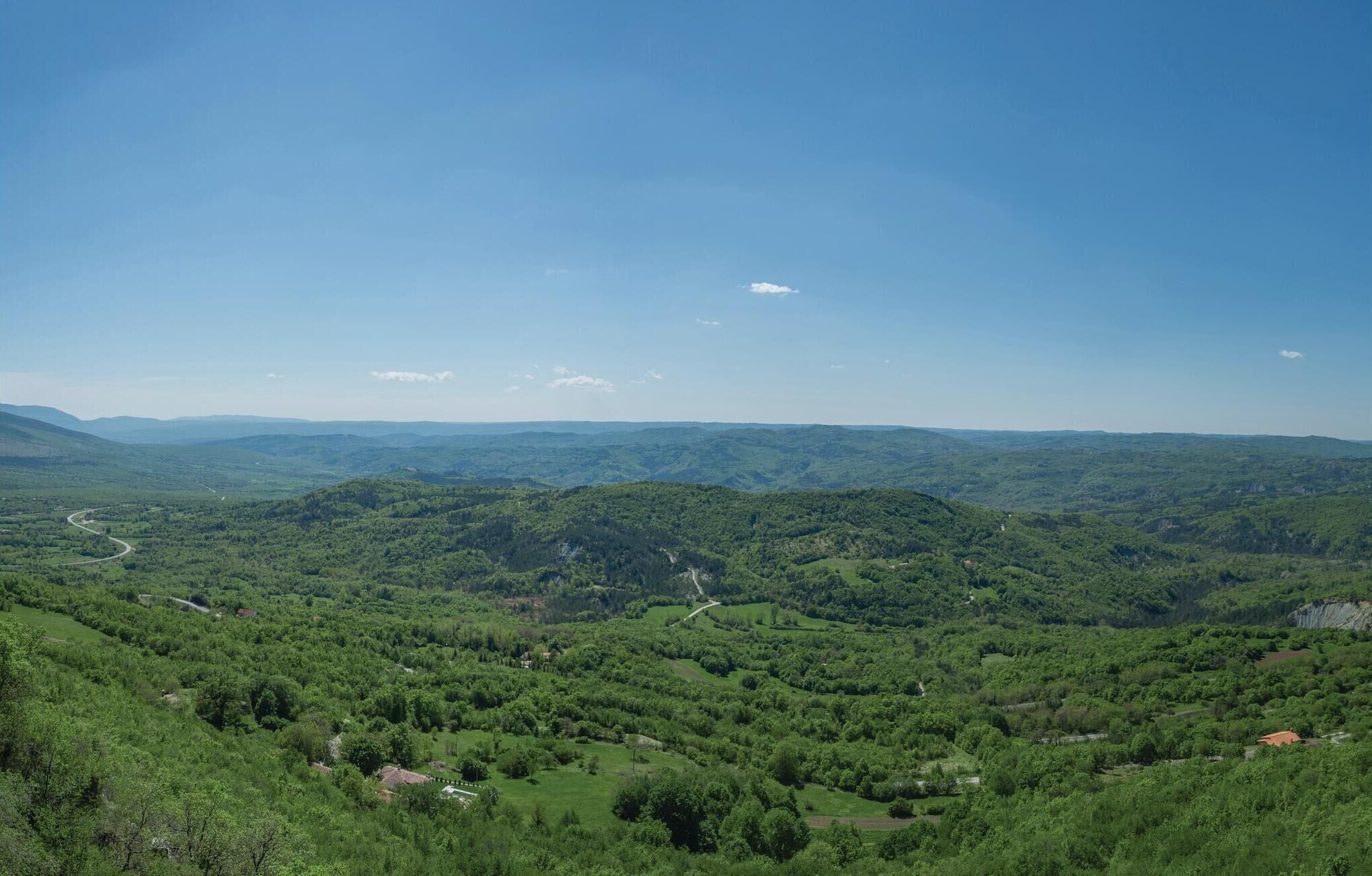 A panoramic view of a mountainous landscape with winding roads and scattered buildings.
