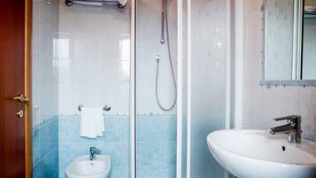 Un bagno con box doccia in vetro, lavabo su piedistallo e bidet.