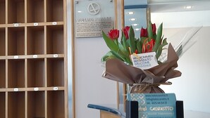 Zona de recepción de un hotel con un panel de madera, un cartel de bienvenida e información de contacto del hotel.