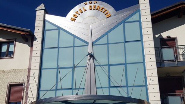 Un hotel de diseño moderno distintivo, con una amplia fachada de vidrio y un cartel llamativo que dice "HOTEL CERETON".