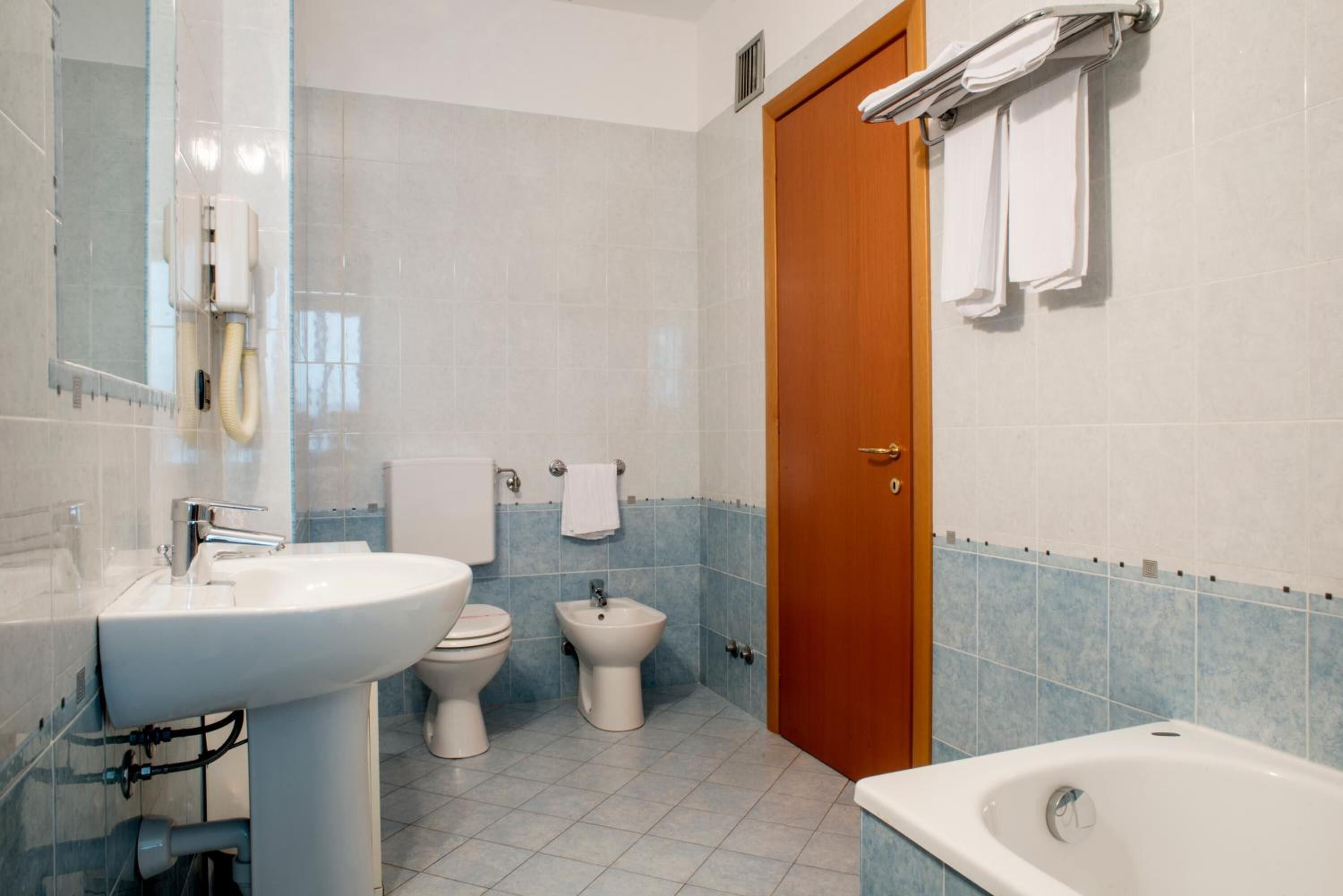 A bathroom with a sink, toilet, bidet, and bathtub.