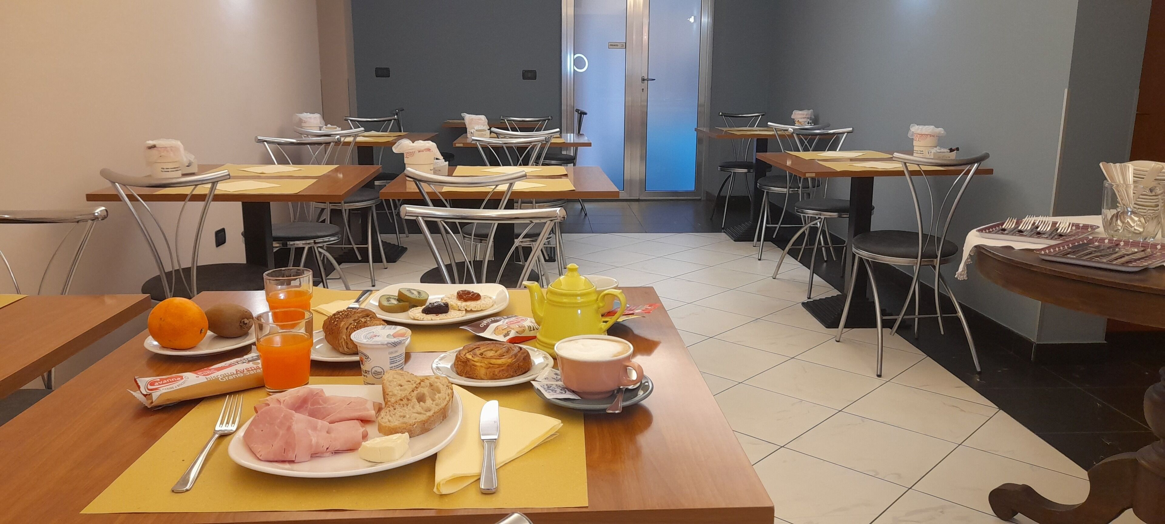 A dining area with tables set for breakfast, including plates of food, drinks, and utensils.