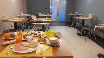 A dining area with tables set for breakfast, including plates of food, drinks, and utensils.