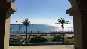 A view through an archway overlooking a beach with palm trees and a clear blue sky. - OwlStay The Salt (Hualien City)