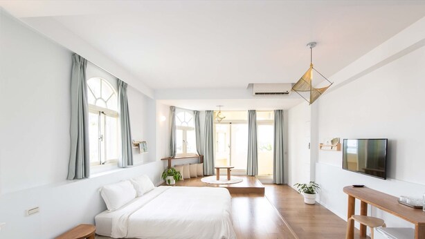A modern hotel room with two beds, a desk, a TV, and large windows with curtains. - OwlStay The Salt (Hualien City)