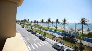 A coastal road with parked cars, a pedestrian crossing, and a restaurant with outdoor seating. - OwlStay The Salt (Hualien City)
