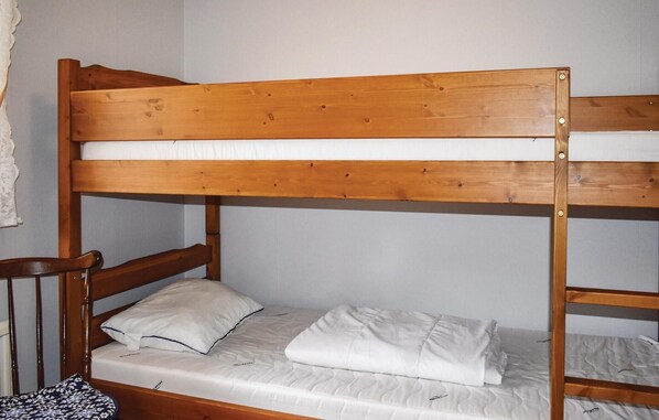 Una cama litera con estructura de madera y ropa de cama blanca.
