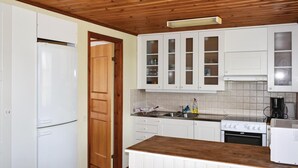 Une cuisine avec des armoires blanches, un plafond en bois et une cuisinière encastrée.