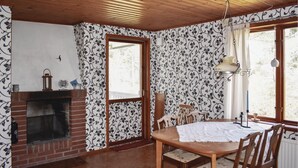 Une pièce avec une cheminée, une table à manger avec des chaises, un lustre et un papier peint à motifs.
