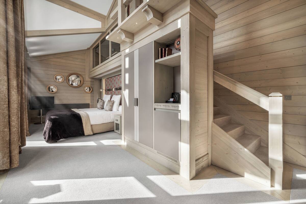 Um quarto com uma cama, um guarda-roupa e uma escada.