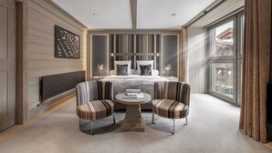 A modern bedroom with a large bed, a TV, a fireplace, and a view of the outside. - Le K2 Djola (Courchevel)