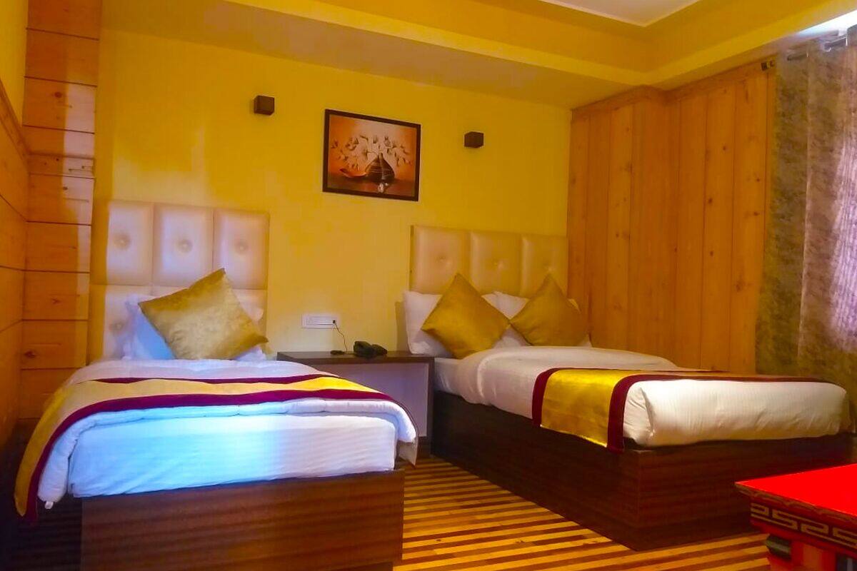Una habitación de hotel con dos camas, cabeceros de madera, alfombra a rayas y un cuadro en la pared.