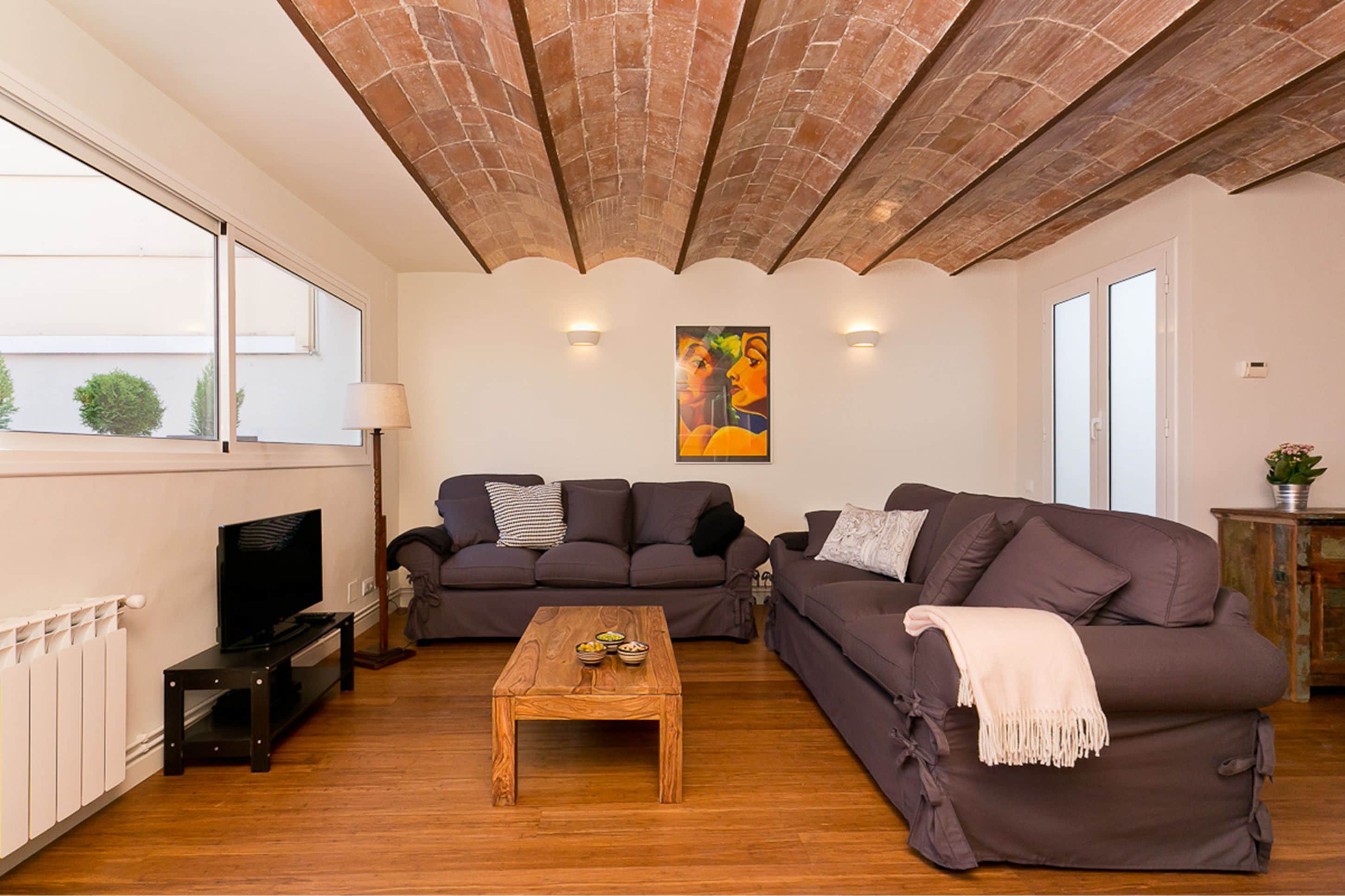 Una sala de estar con dos sofás, una mesa de centro de madera, un televisor sobre un mueble bajo y un cuadro en la pared.