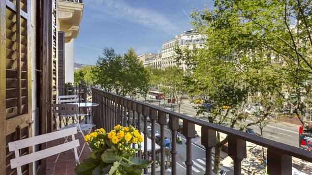 A balcony with a view of a city street, a building with balconies, and a flower arrangement. - BCN Paseo de Gracia Rocamora Apartments (Barcelona)