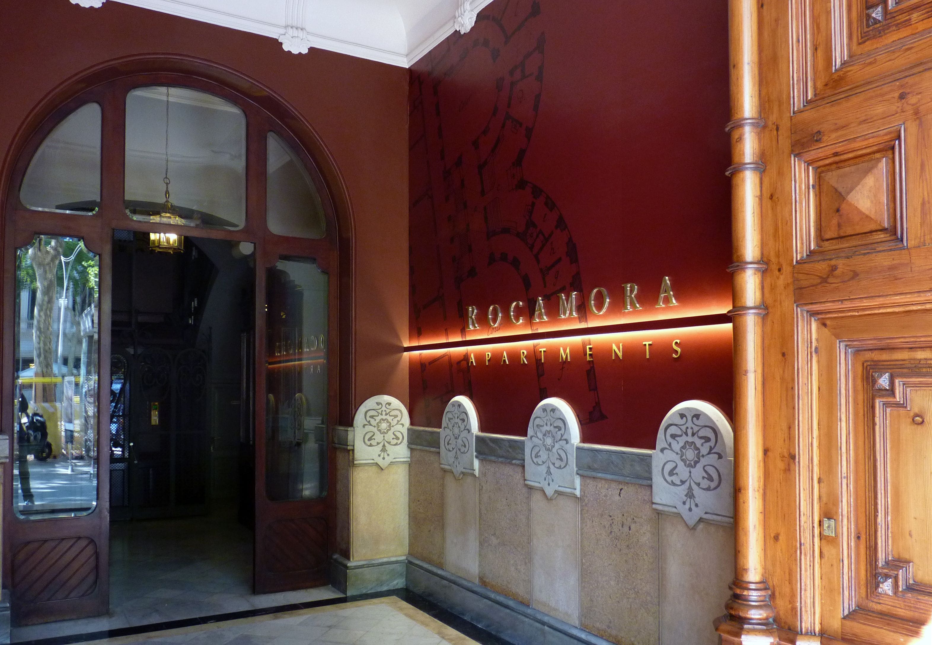 Rocamora apartments entrance with a large arched doorway, decorative moldings, and a sign above the entrance.