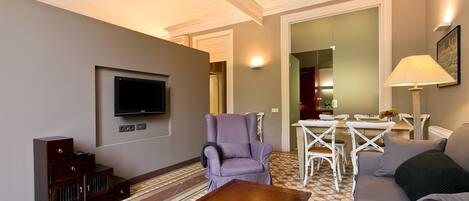 A living room with a flat-screen TV, a purple armchair, a wooden coffee table, and a sofa.