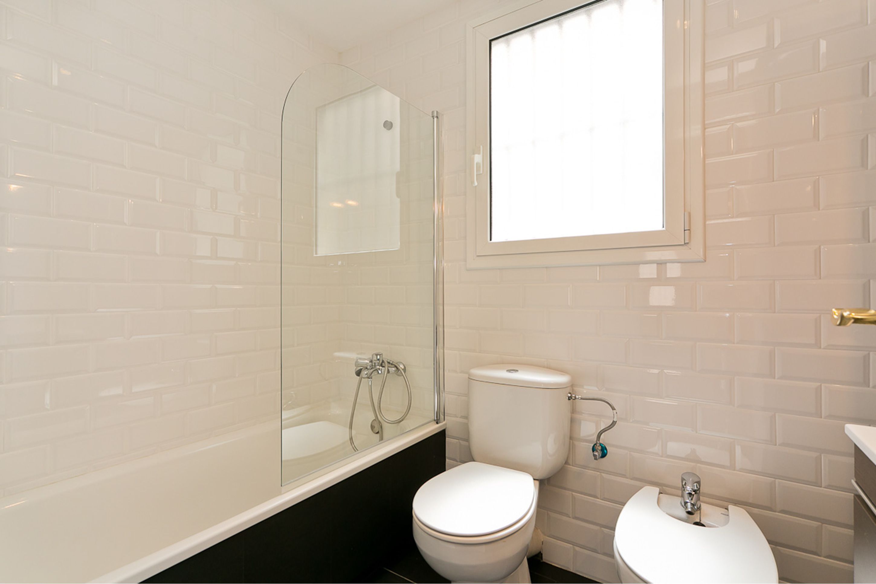 Ein Badezimmer mit einer gläsernen Duschkabine, einer weißen Toilette und einem Waschbecken mit Spiegel darüber.