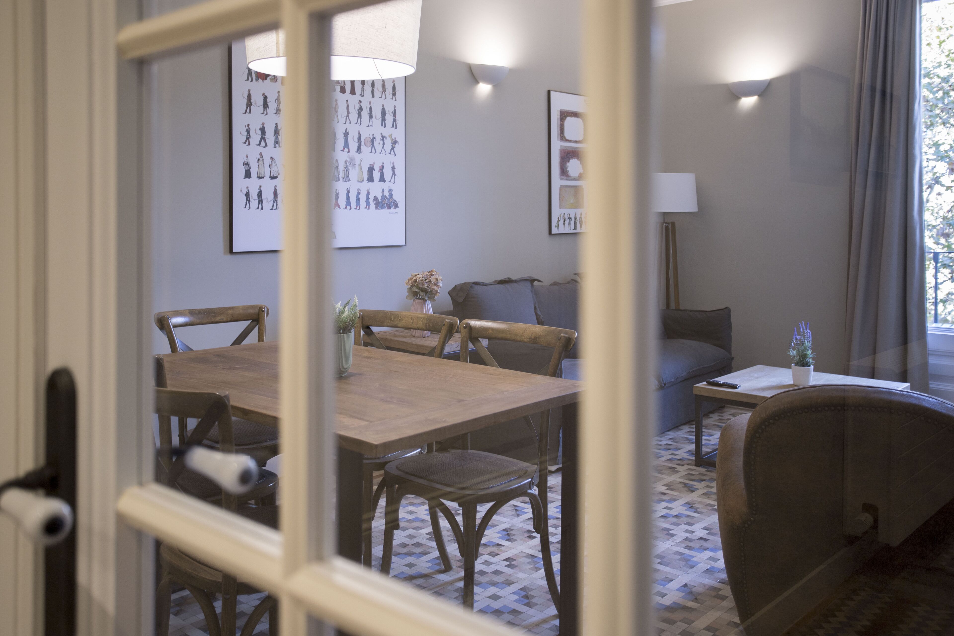 A dining area with a wooden table and chairs, a sofa, and a lamp.