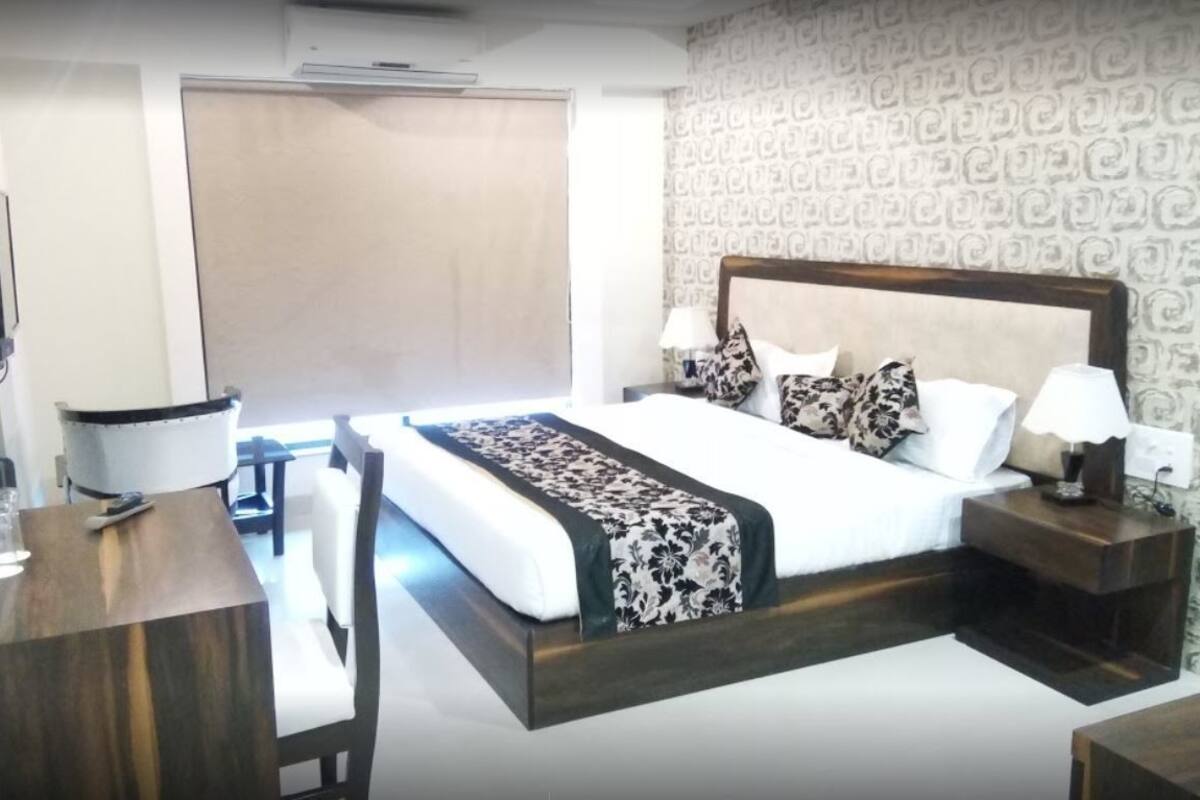 A hotel room with a bed, bedside tables, a desk, and a chair.