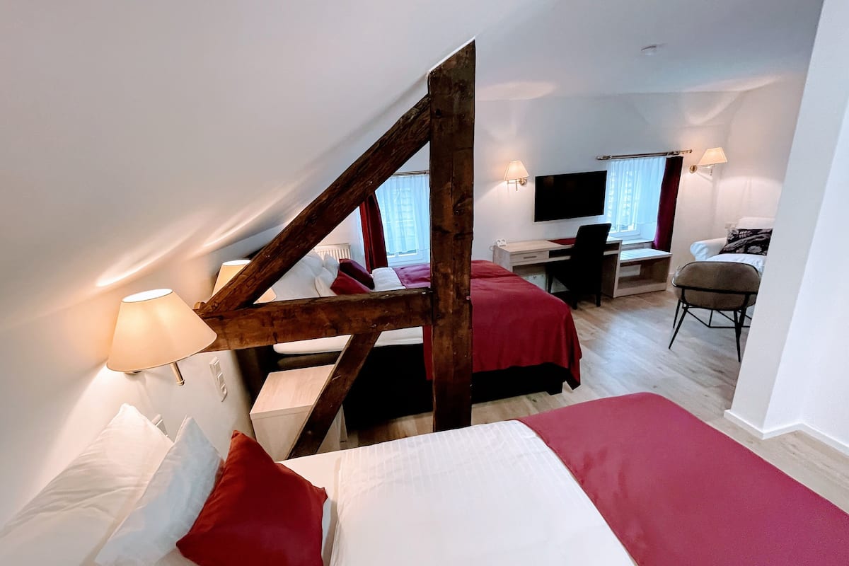 A bedroom with two beds, a desk, a chair, and a TV.