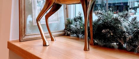 A metallic deer sculpture with antlers and a ball ornament on a wooden shelf.