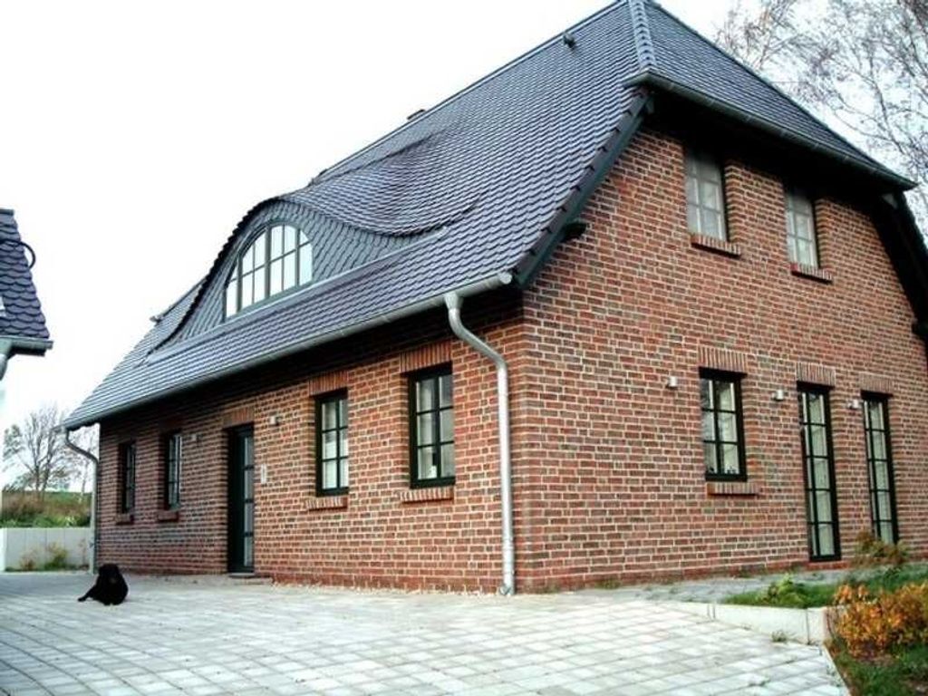 Ein Gebäude aus Ziegelsteinen mit einem geneigten Dach und mehreren Fenstern.